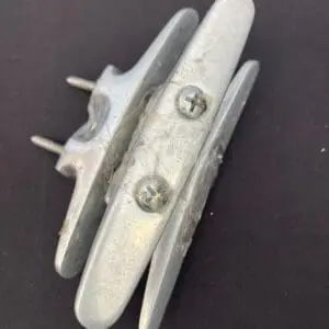 A pair of Aluminum cleats with stainless steal screws on a black surface.