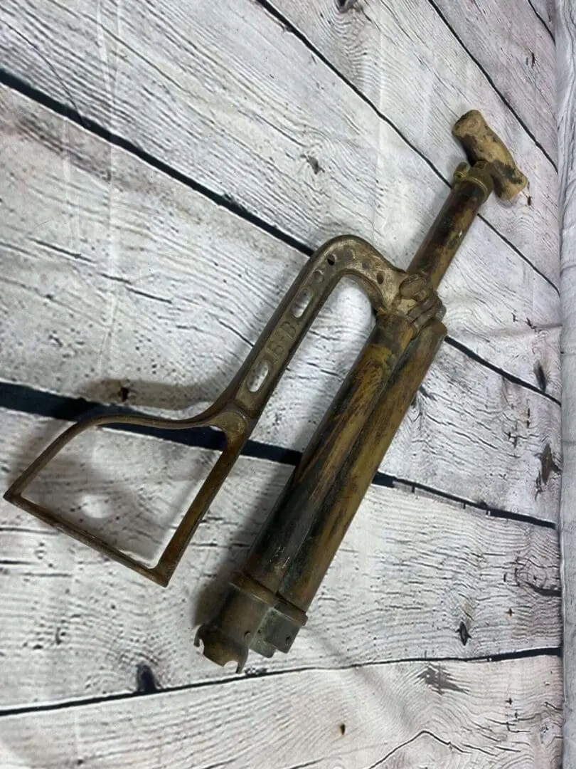 An old brass Ashland USA Bilge Pump on a wooden surface.