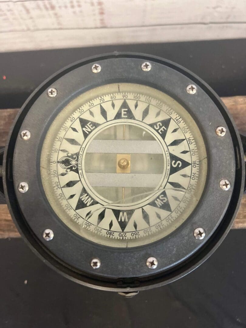 An Aluminum Binnacle Compass on top of a wooden base.