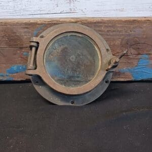 A small Brass Porthole #10 on a wooden surface.