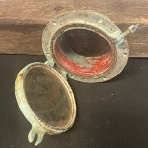 A small Brass Porthole # 10 mirror on top of a wooden table.