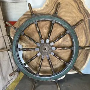 A small craft wheel with wooden handles 3 is sitting on top of a piece of wood.