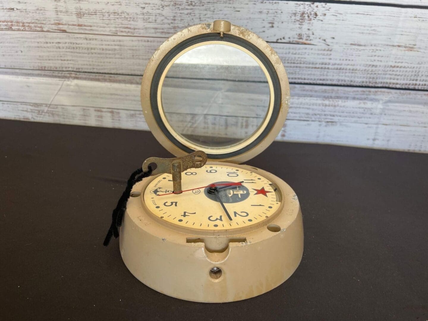 A Russian submarine clock with a mirror sitting on top of it.