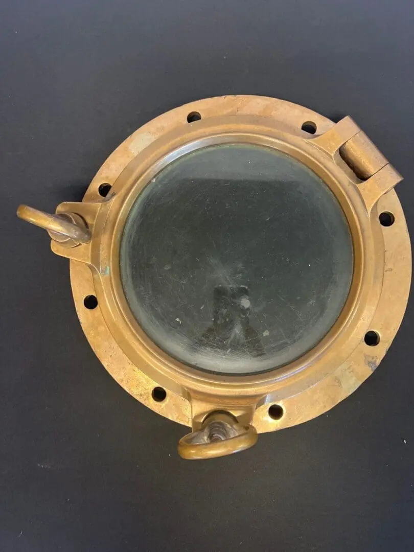 A porthole window with the reflection of a ship in it.