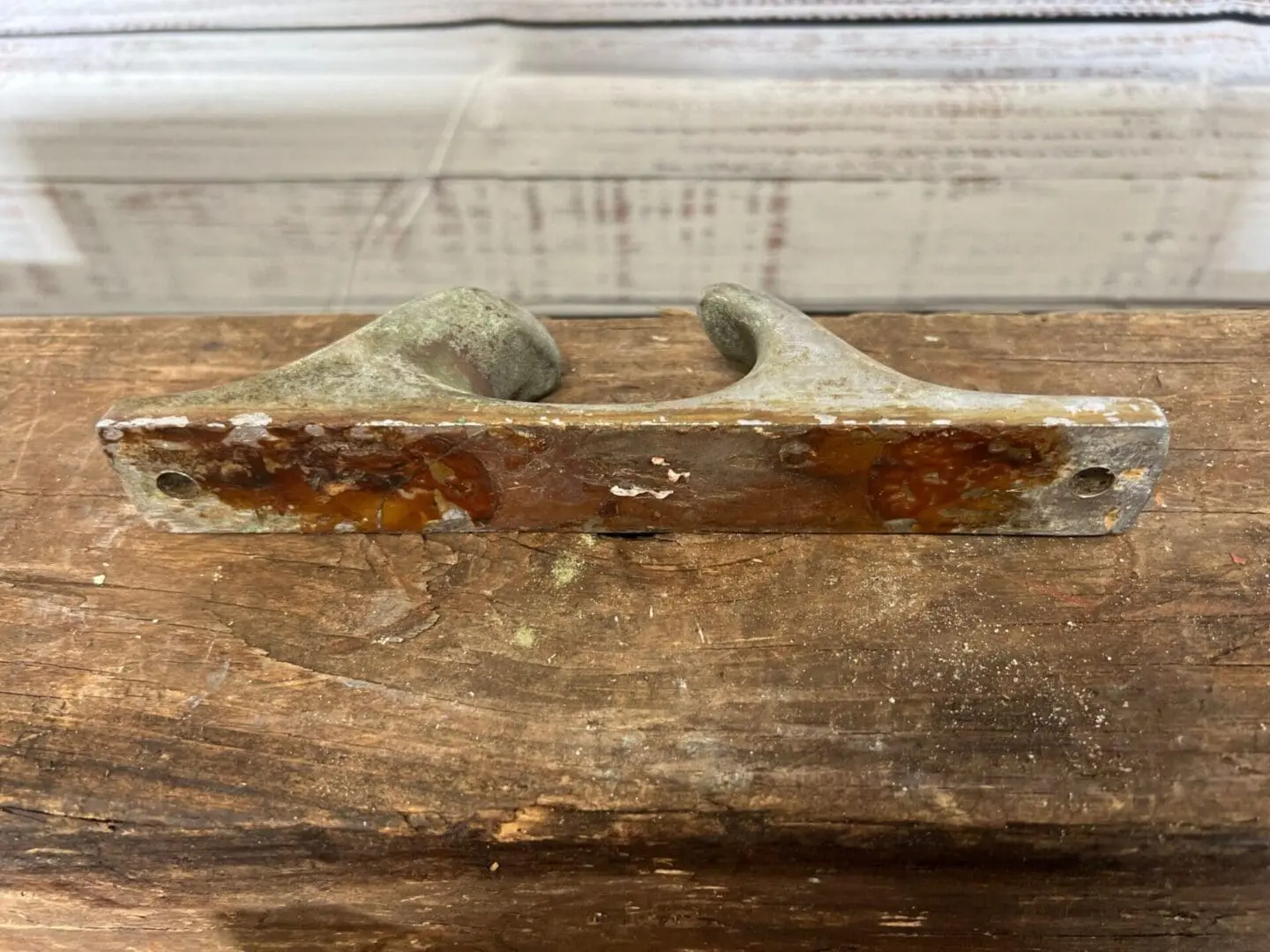 A rusty handle on top of a wooden bench.