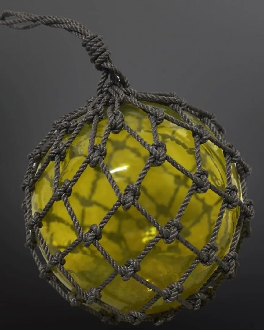 A yellow glass float with black netting.