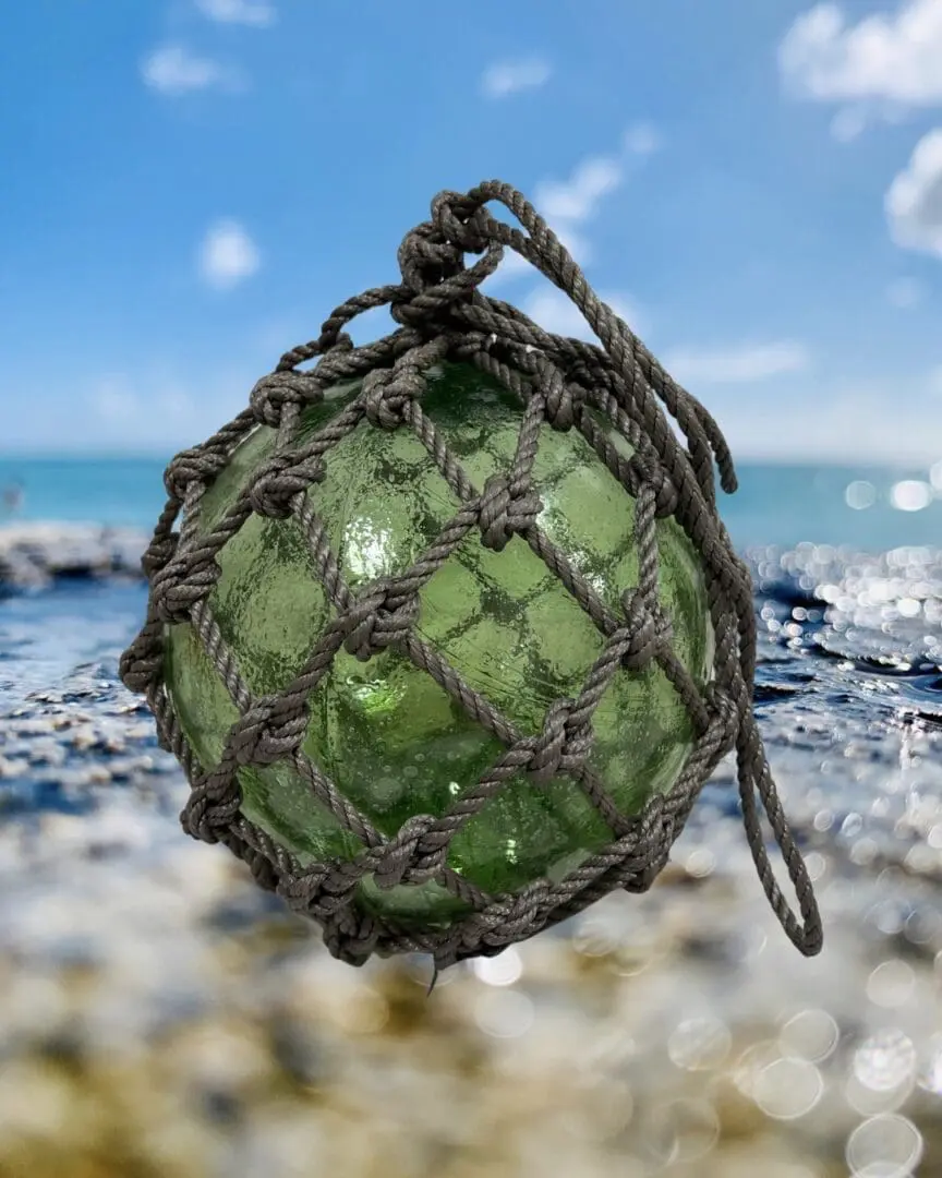 A green ball with rope on the beach.