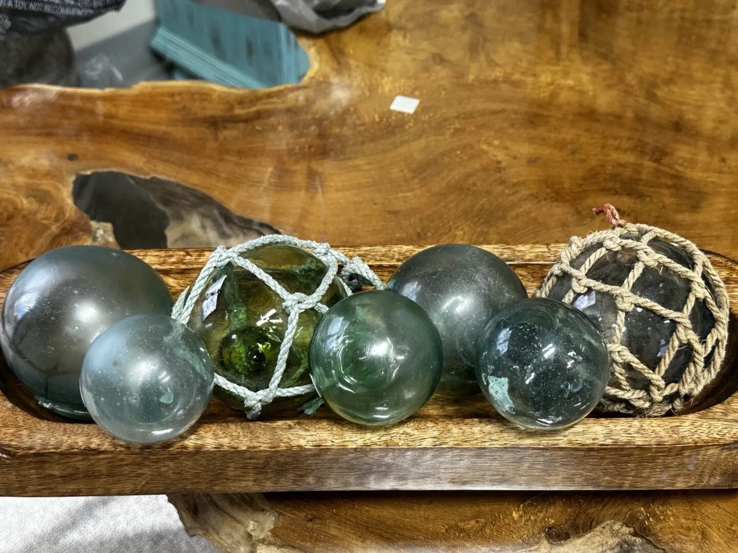 A wooden tray holding glass floats and rope.