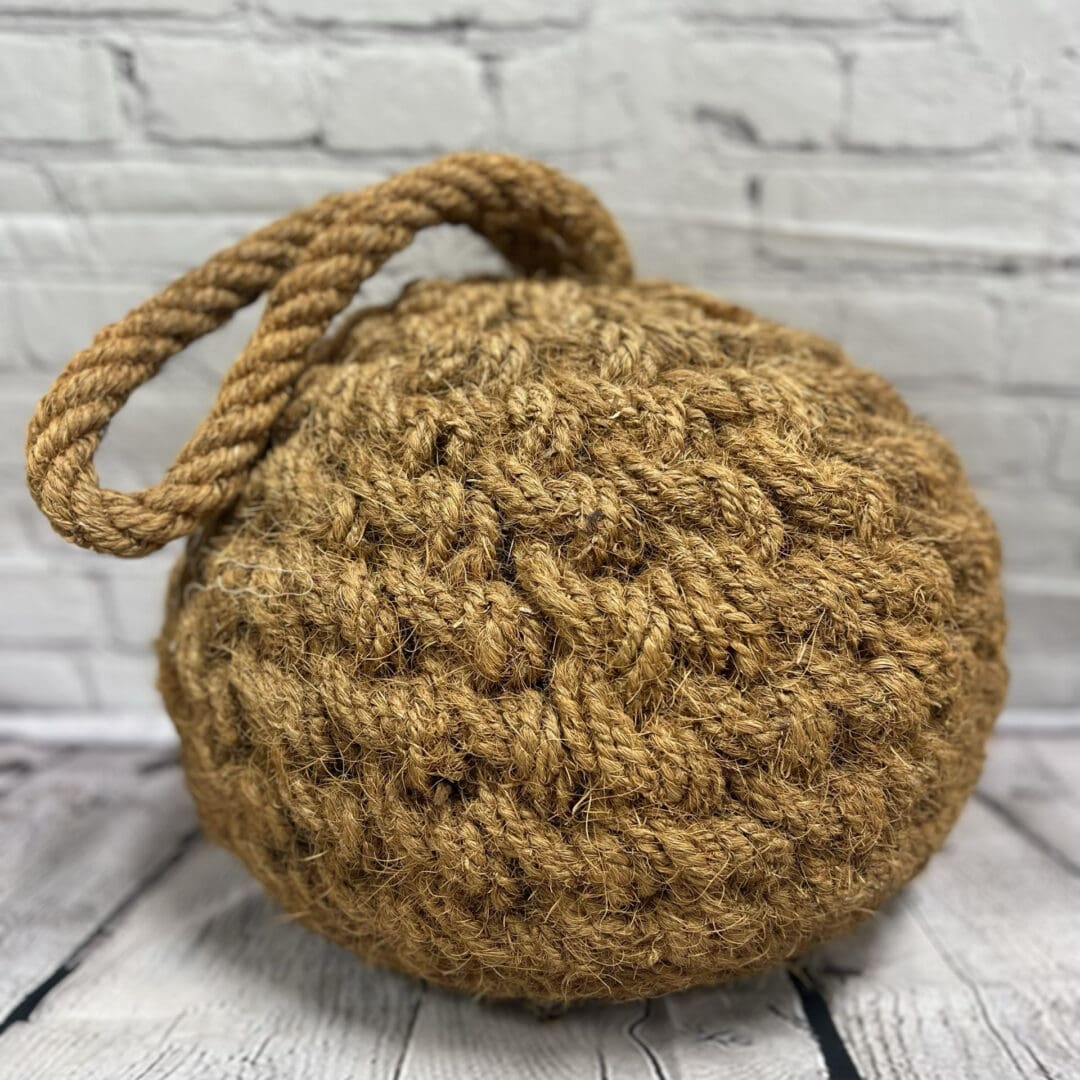 A brown ball with rope handle on top of a table.