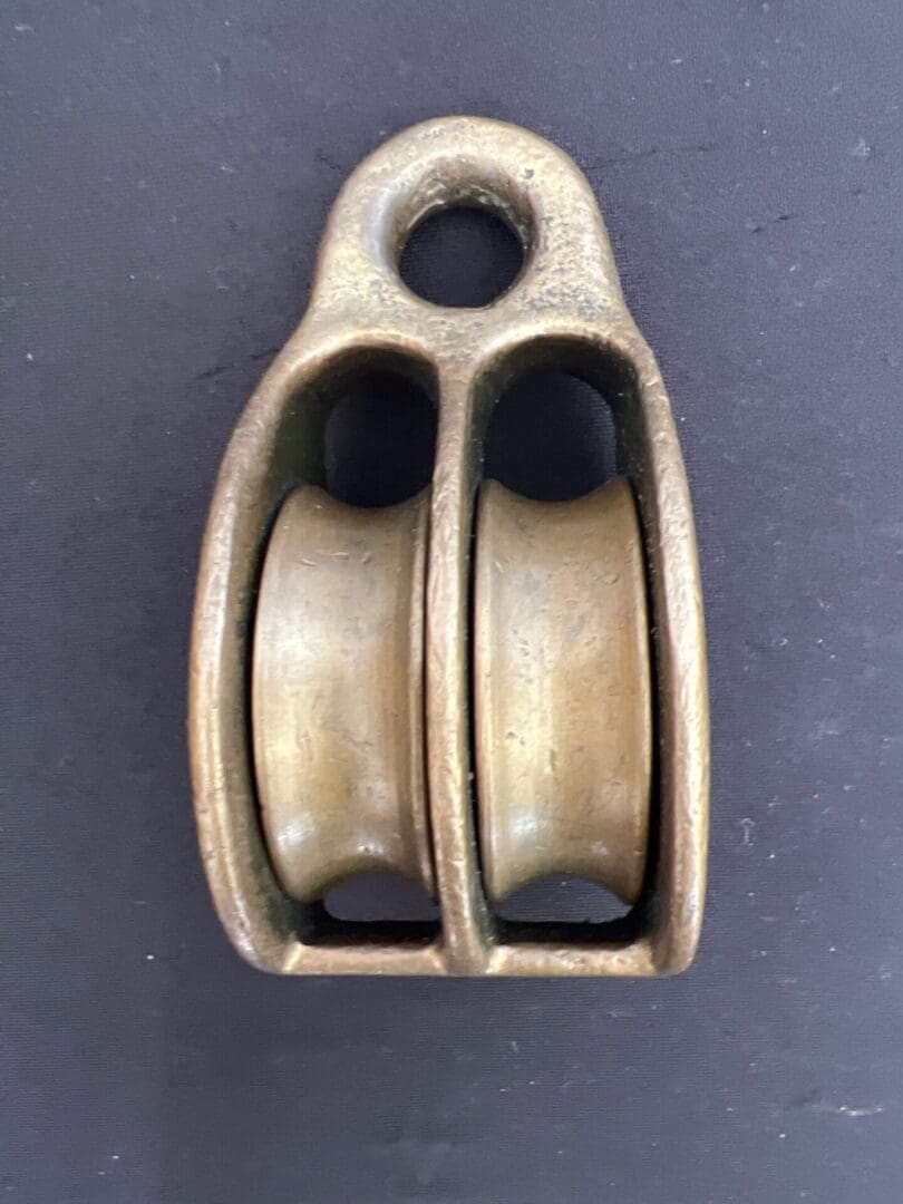 A brass double pulley on top of a black surface.