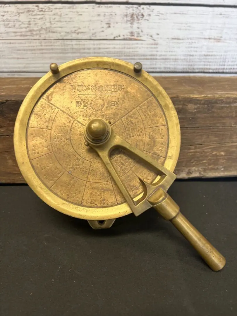 A gold colored compass sitting on top of a table.