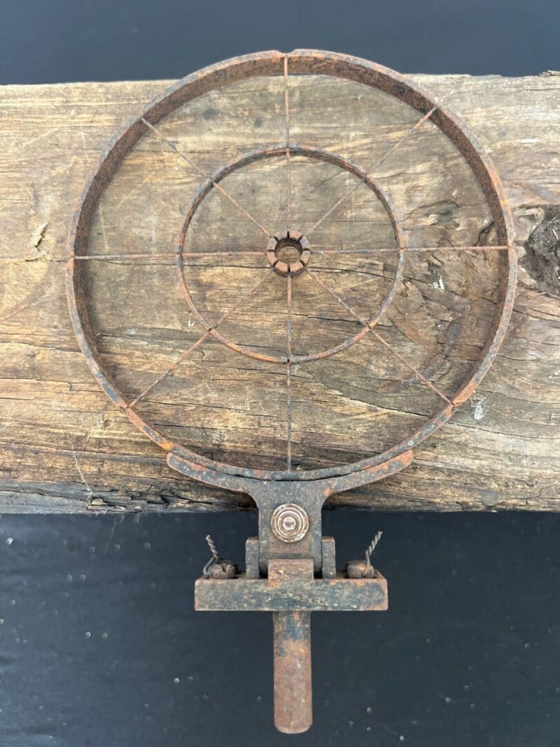 A rusty old iron wheel on top of a wooden table.