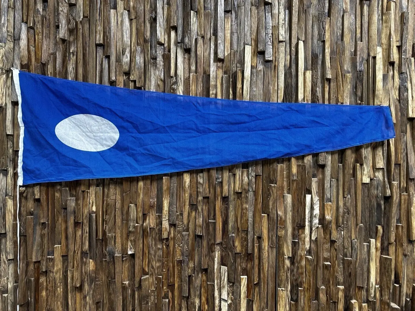 A blue flag hanging on the side of a wooden wall.