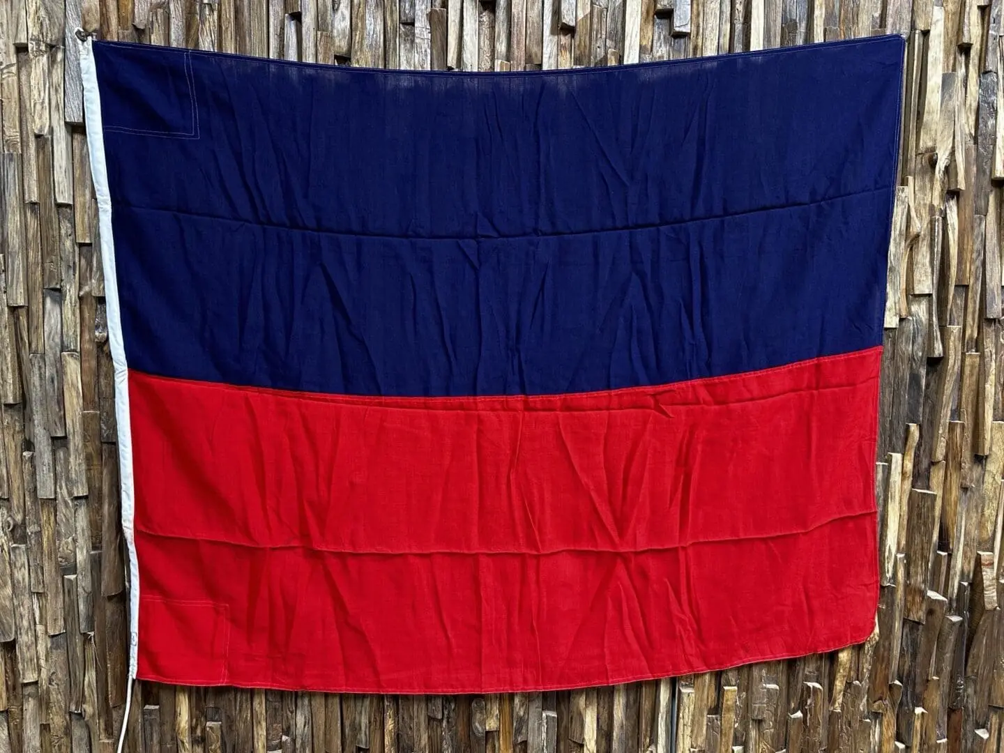 A red and blue flag hanging on the side of a wooden fence.