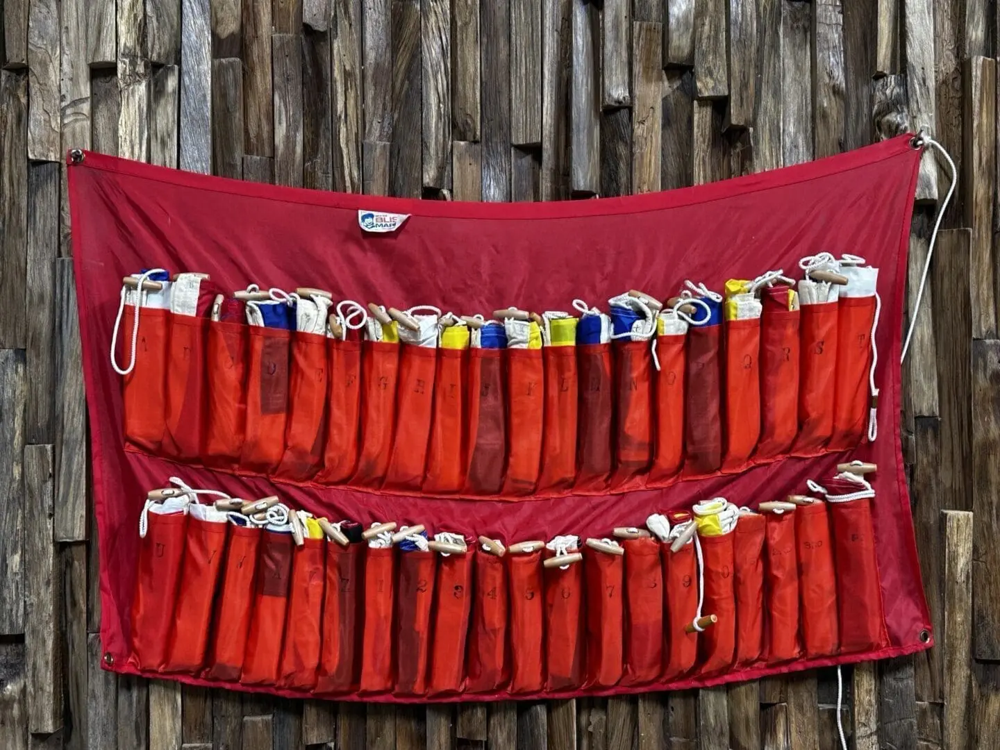 A red bag hanging on the wall of a wooden building.