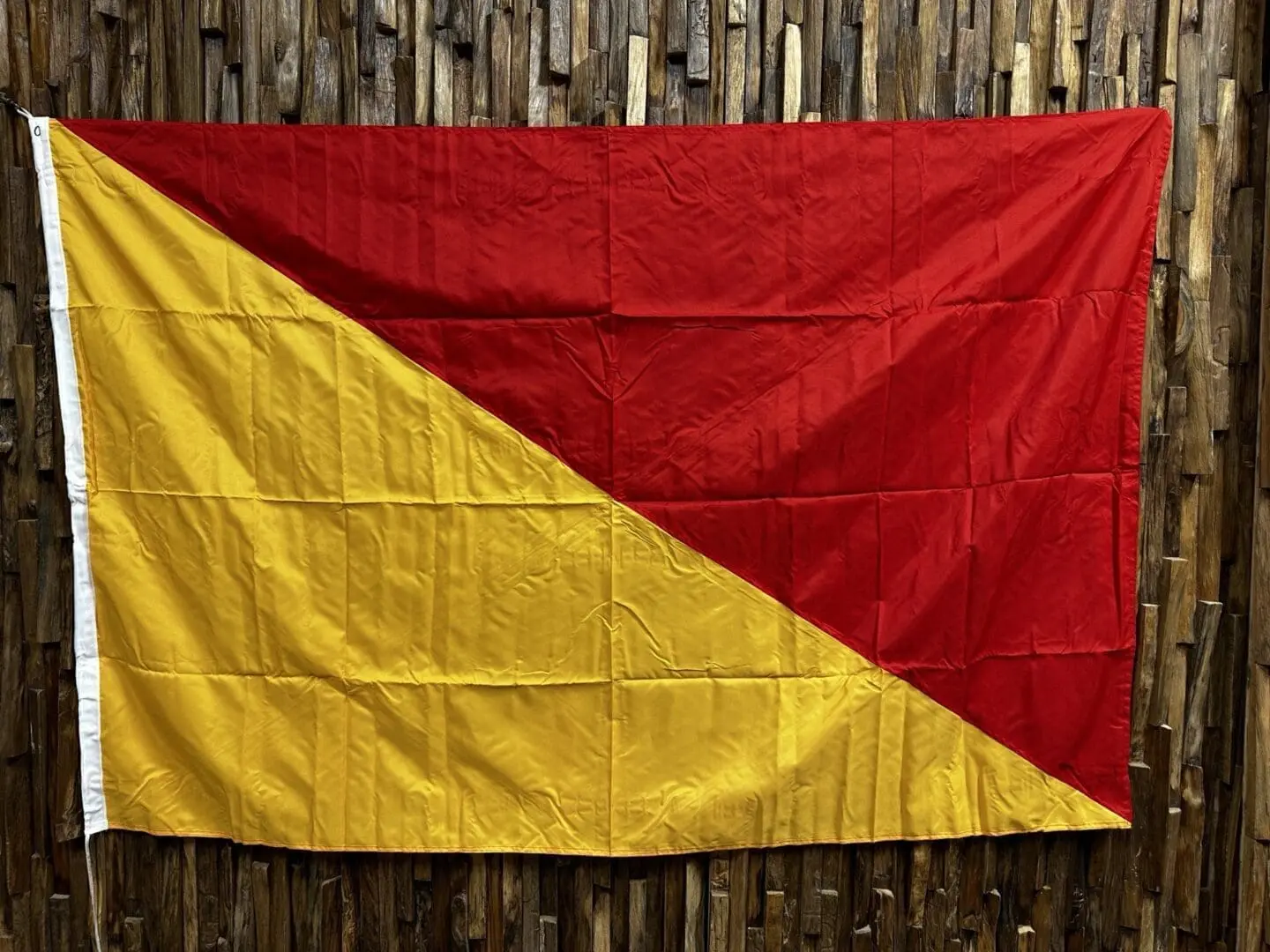 A red and yellow flag hanging on the side of a wooden wall.