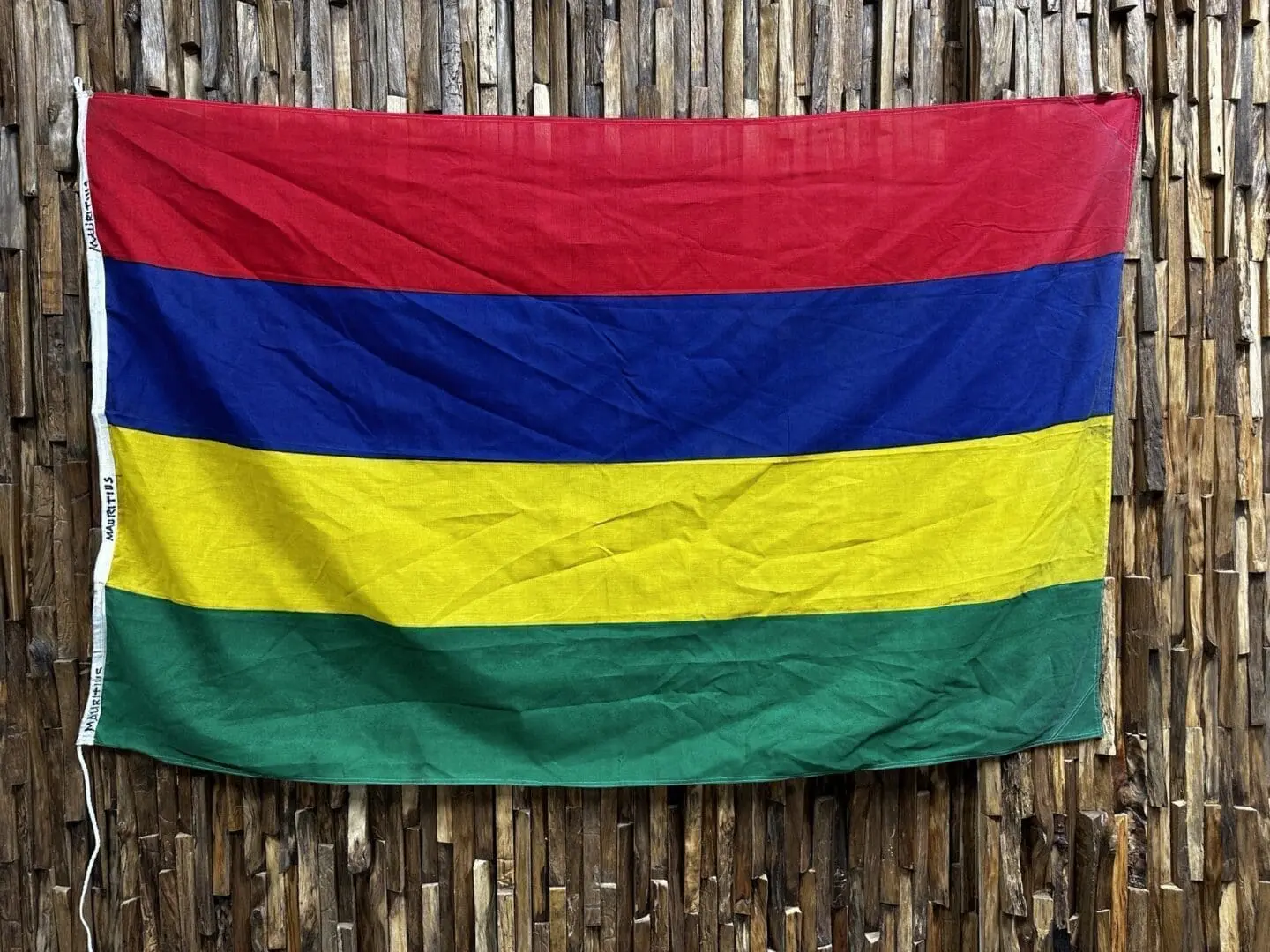 A colorful flag hanging on the side of a wooden fence.