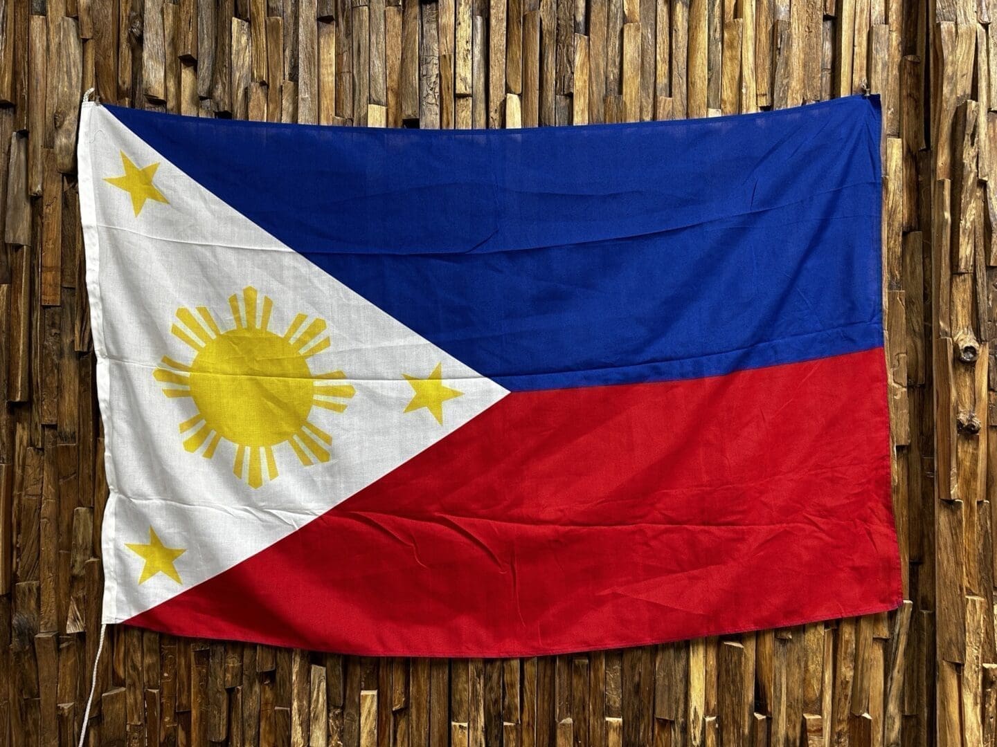 A flag of the philippines hanging on a wooden wall.