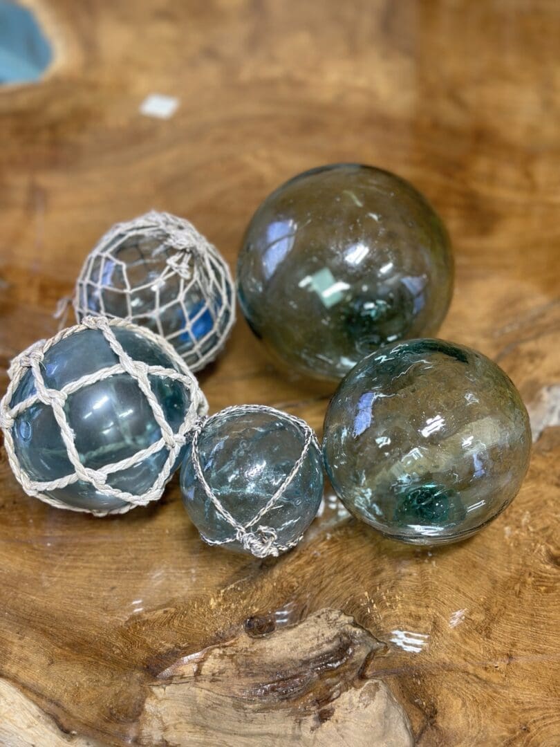 A group of glass floats on top of a wooden table.