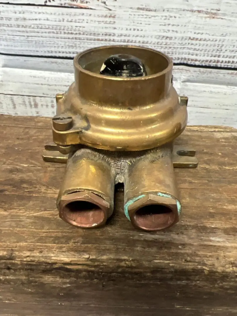 A close up of the top part of an old brass water pump.