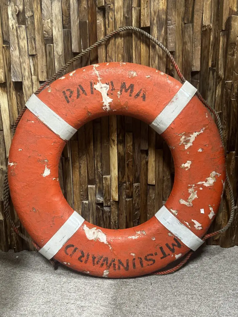 Red and white life preserver with text.