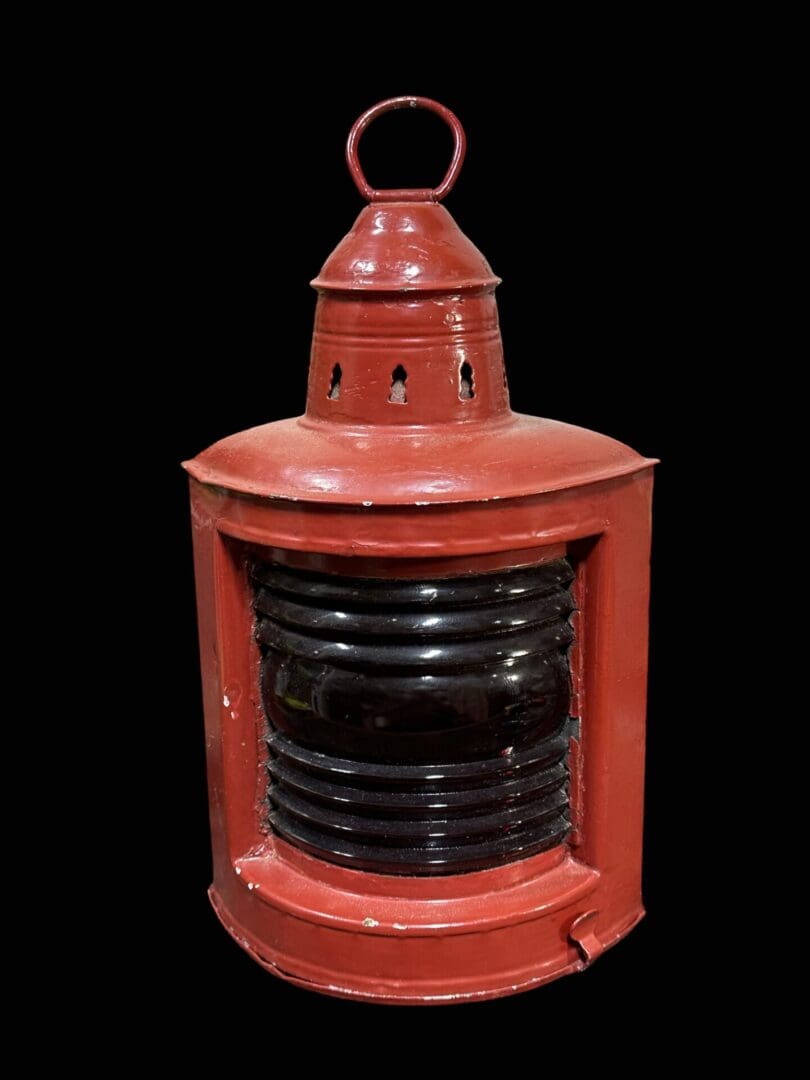 Red metal nautical lantern with lens.