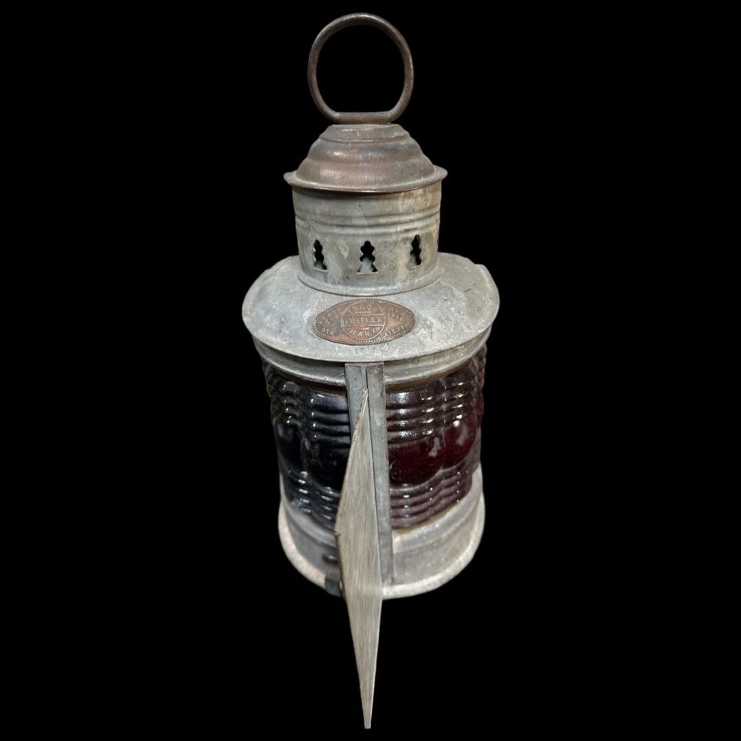 Antique metal lantern with red glass lens.