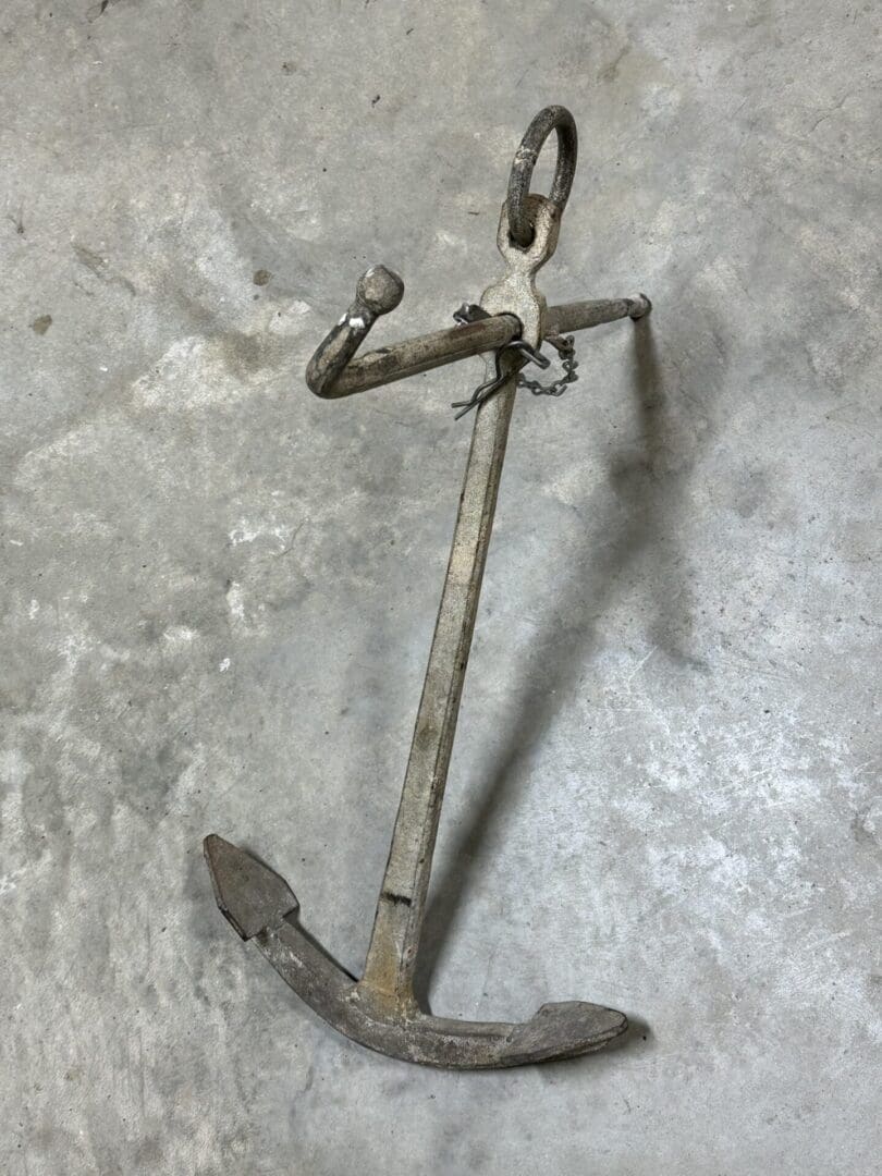 A rusty metal ship anchor on a concrete floor.