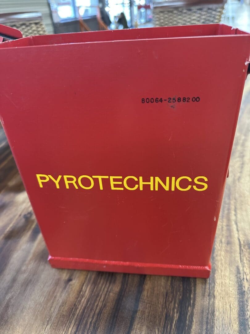 A red container labeled 'PYROTECHNICS' in yellow letters on a wooden surface.
