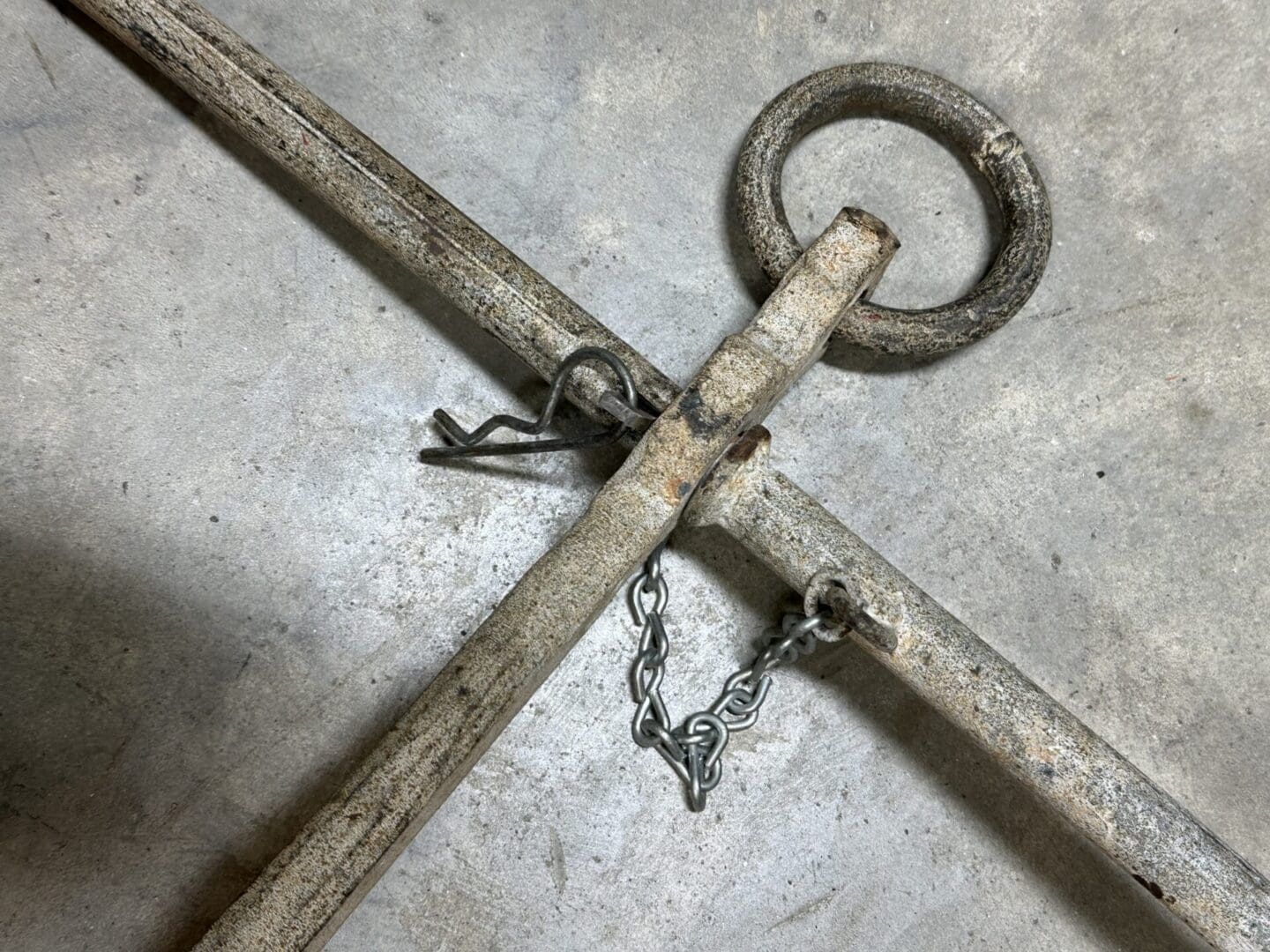 Close-up of a rusty metal anchor on a concrete surface.
