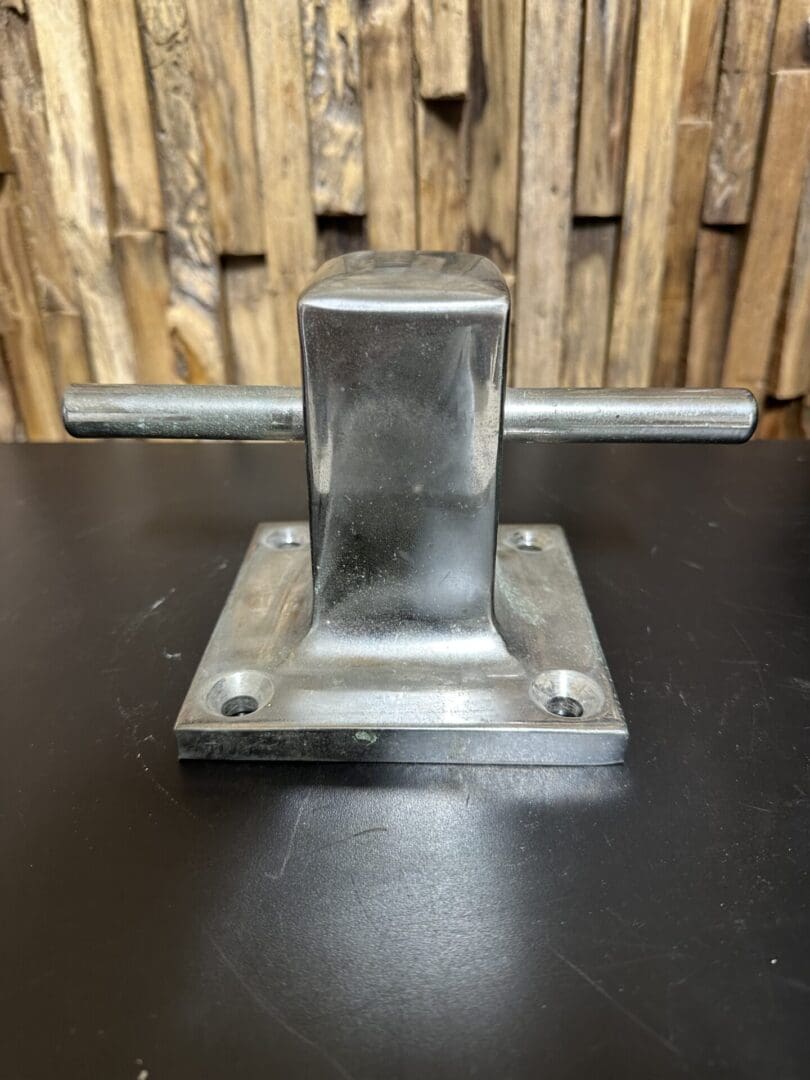 Metal cleat for securing ropes, mounted on a flat surface.