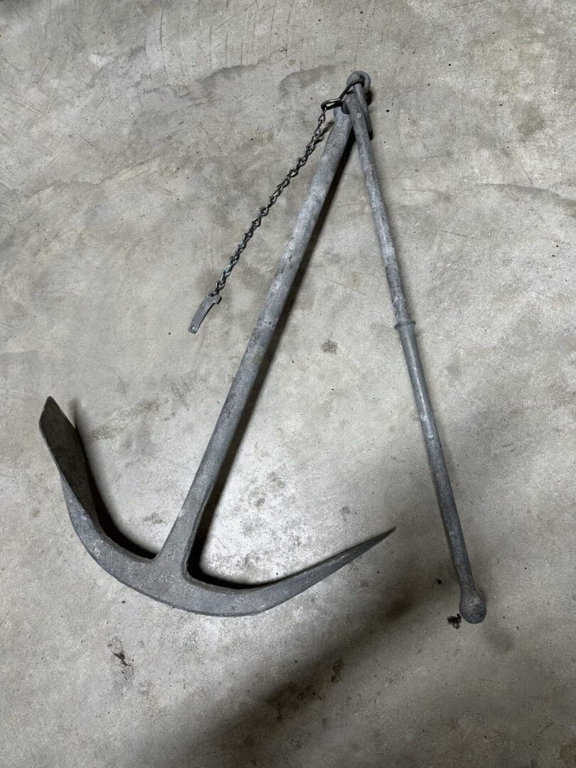 Old metal anchor with a chain on a concrete floor.