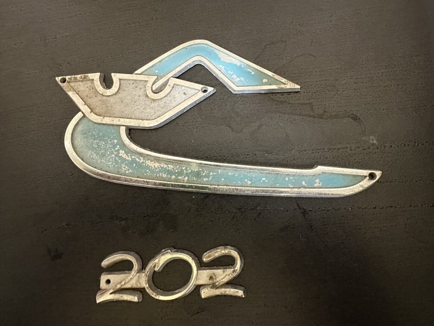 Vintage metal badge with a boat design and the number 202.