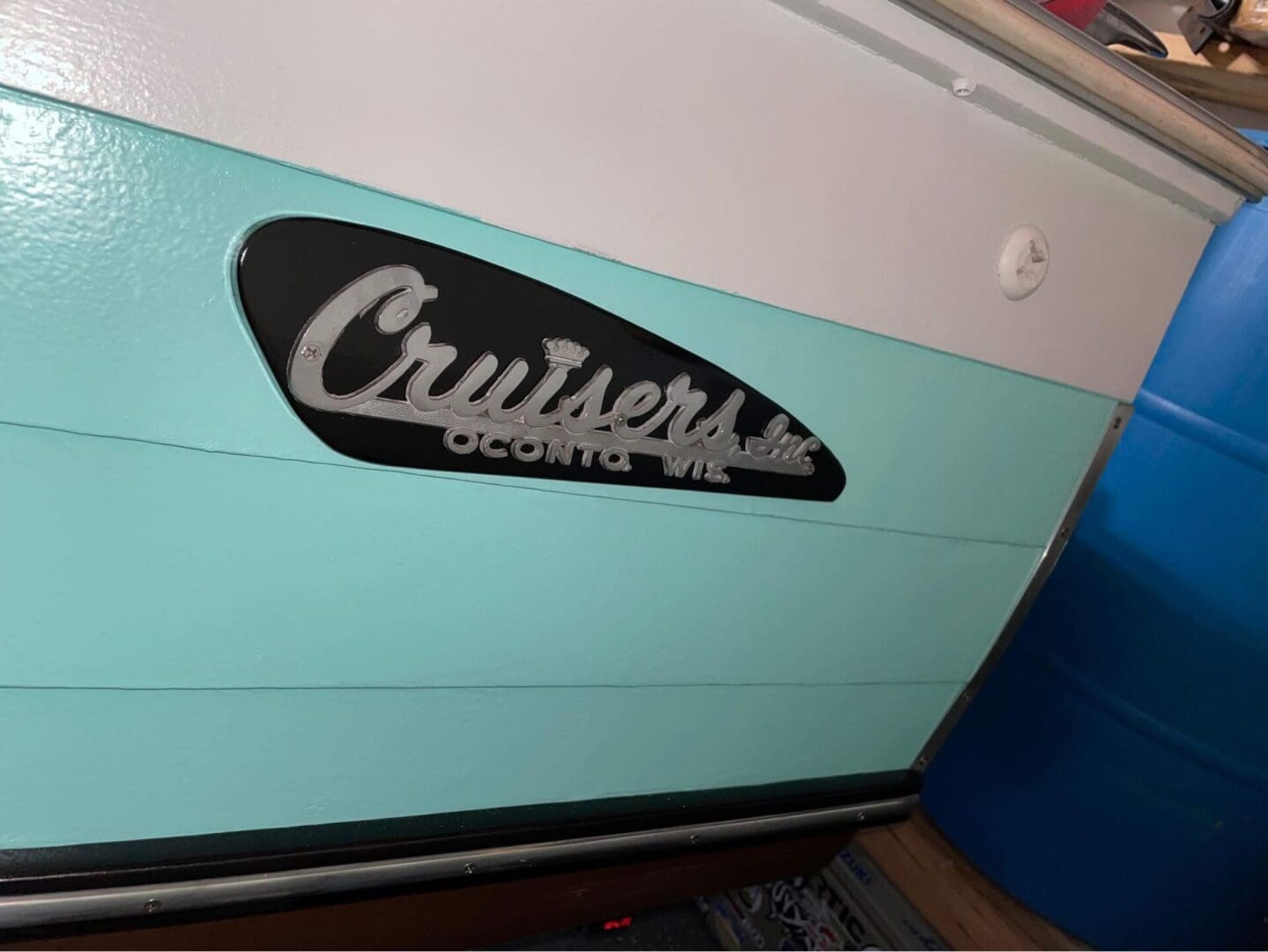 Close-up of a teal and white boat with a Cruisers Inc. emblem.